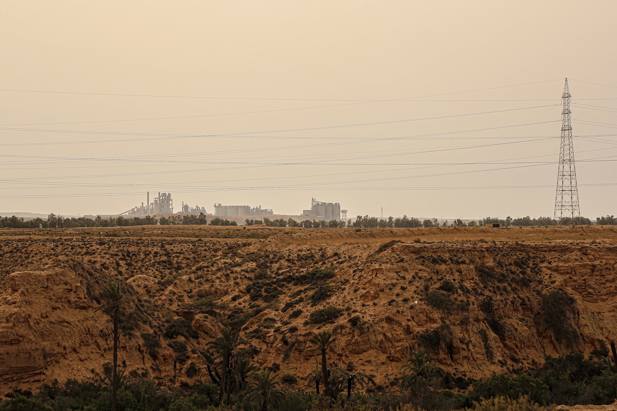 An industrial plant on the horizon beyond the oasis at Chenini