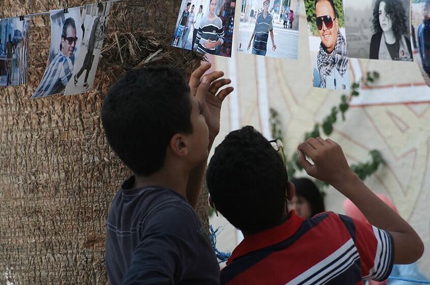 Children reaching up toward the hung portraits