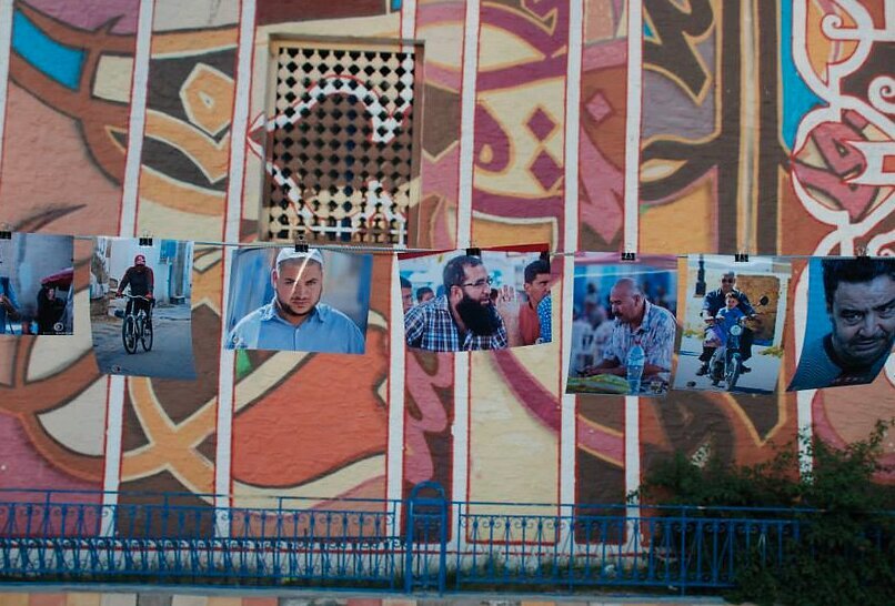 Portraits hung on a line against a painted mural wall