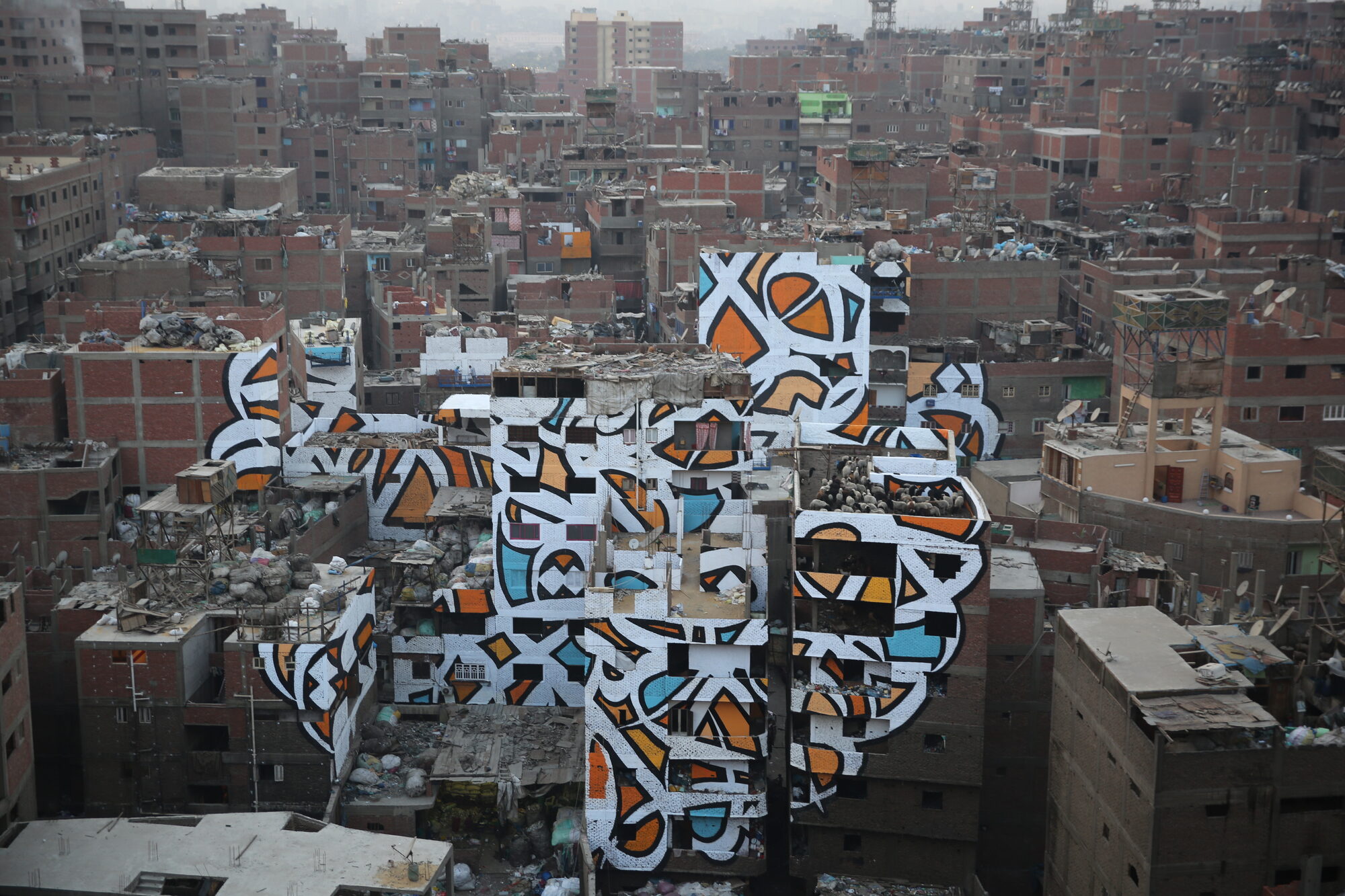 Wide aerial view of the mural at dawn with the Cairo skyline