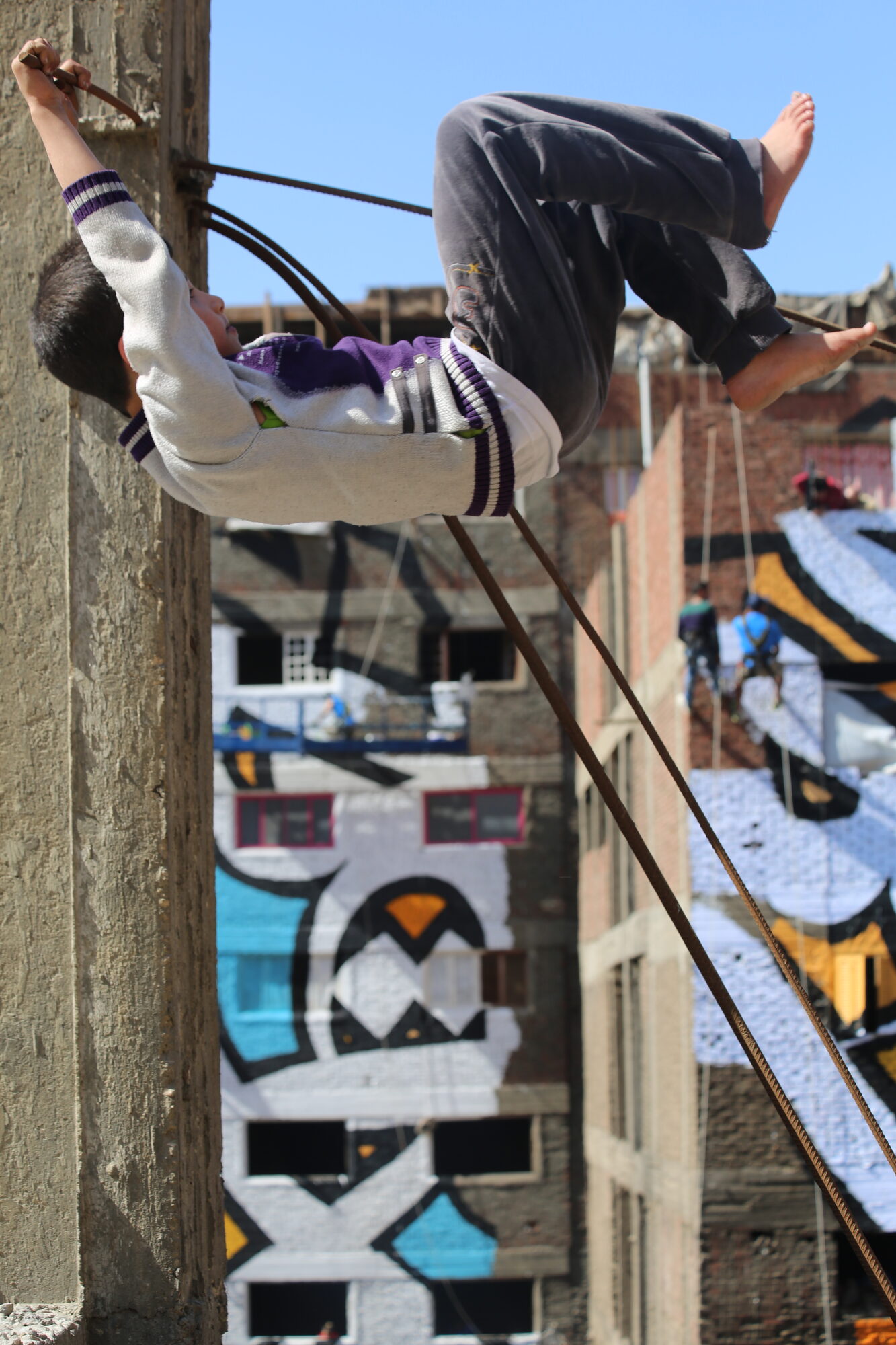 A boy playing on rebar against the mural backdrop