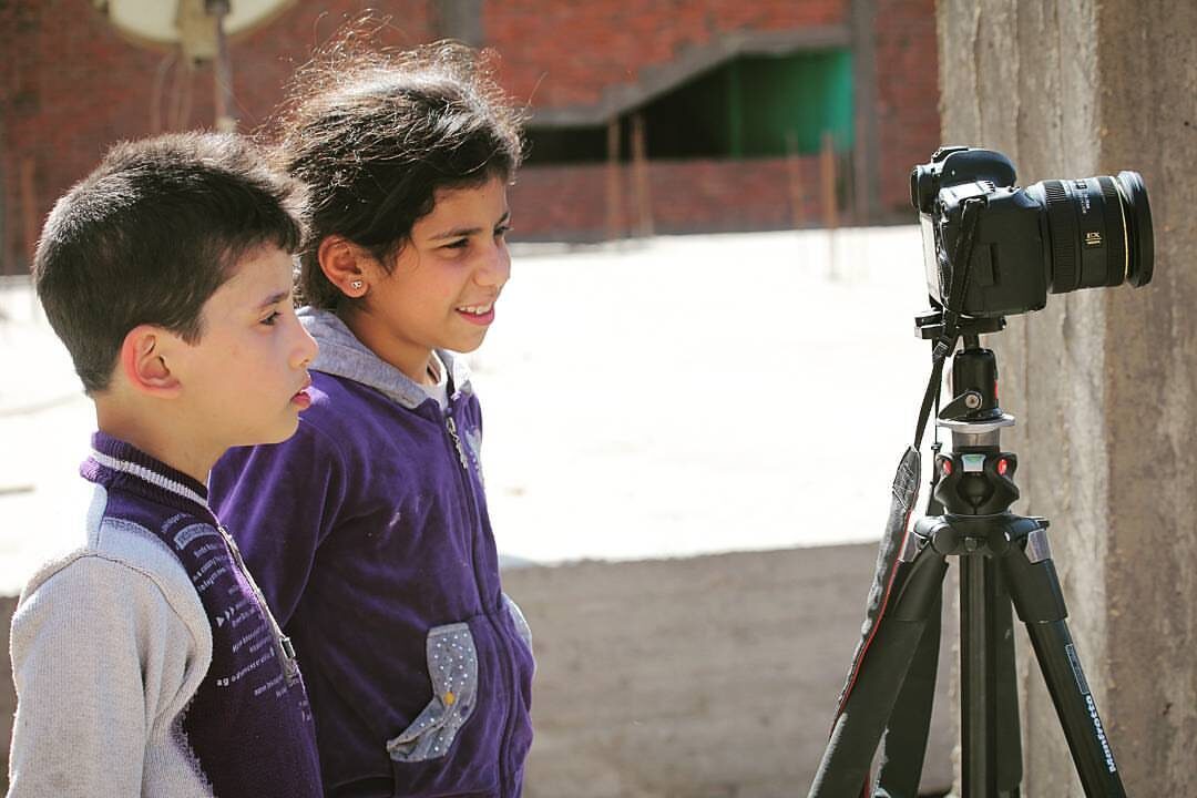 Local children watching the camera on a tripod
