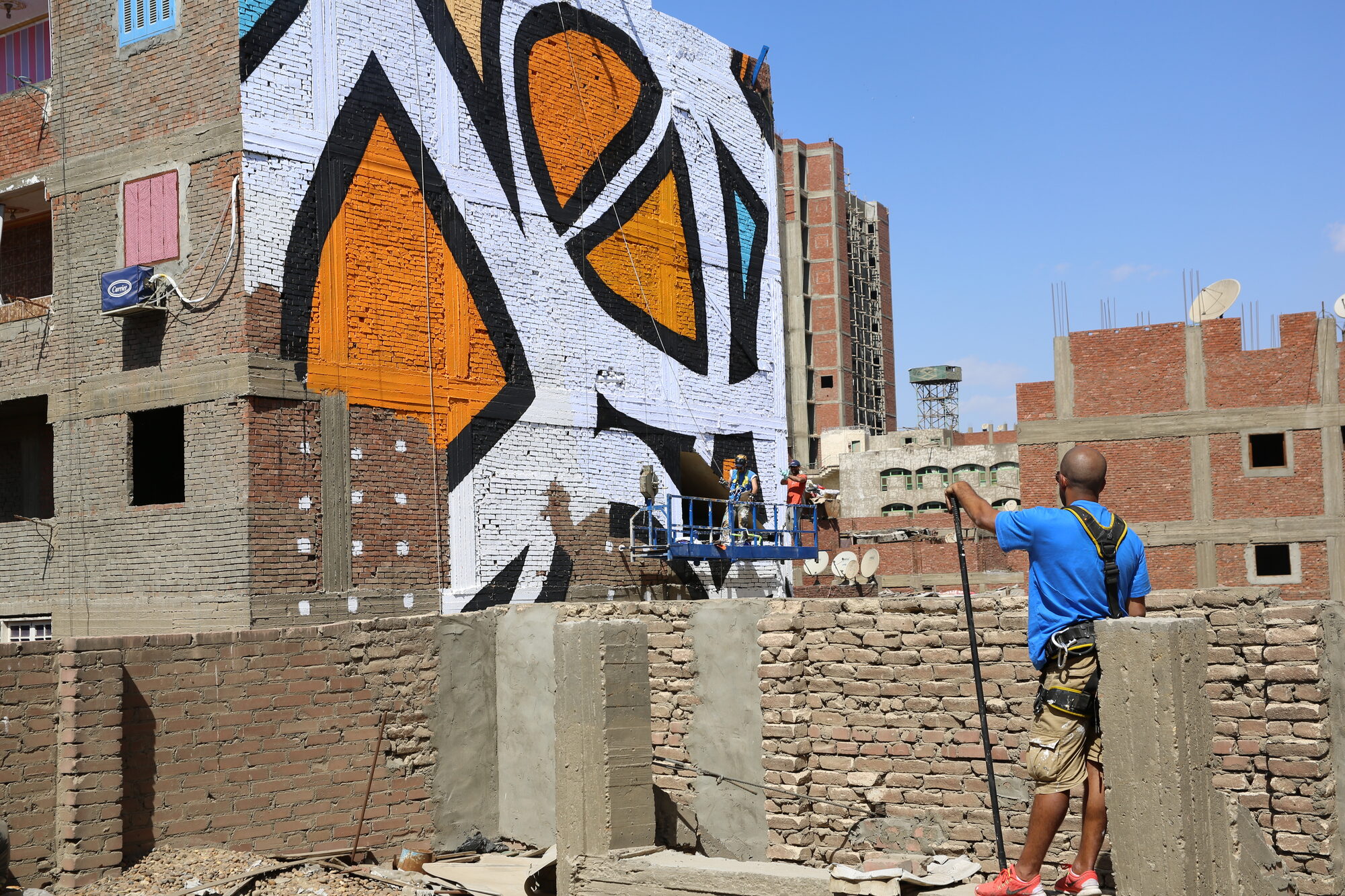 A worker looking up at the mural in progress