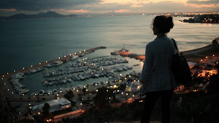 A woman looking out over Tunis bay at sunset, a still from Meanwhile in Tunisia